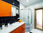 Pomarańczowe meble łazienkowe i czarne płytki ceramiczne – projekt nowoczesnej łazienki